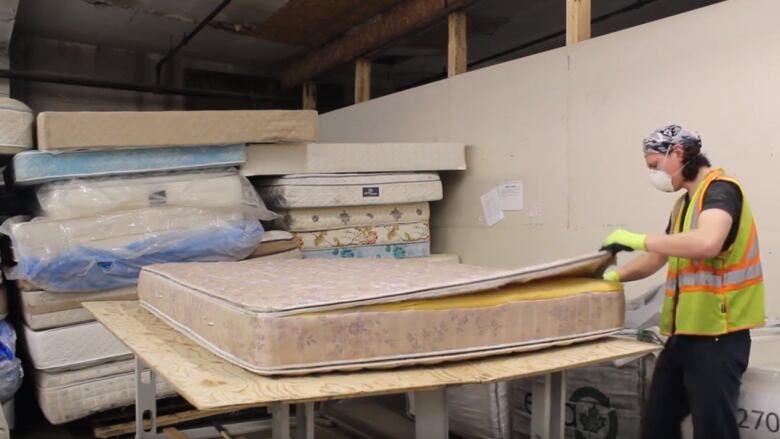 Worker sorting a mattress for recycling